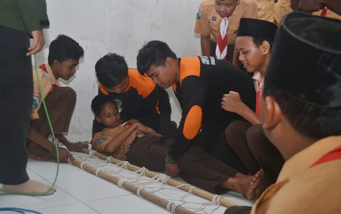 SIMULASI: Siswa MTs Hasanuddin memberikan pertolongan pertama pada korban saat simulasi tanggap bencana gempa bumi, Jumat (26/4). Foto: MUSTAIN/ BANGSAONLINE