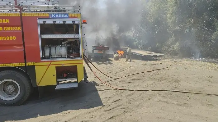 Petugas DKPP Gresik berusaha memadamkan roll trailer yang terbakar