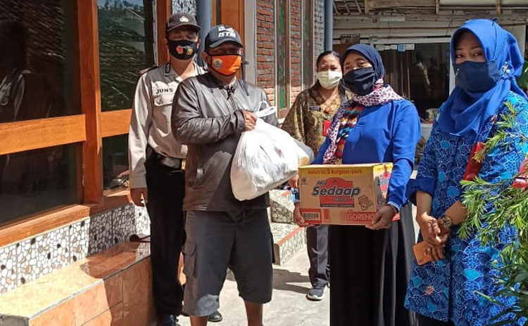 Warga Kampung Tangguh Semeru Songgokerto saat menyerahkan sembako kepada warga konfirm positif Covid-19 yang menjalani isolasi mandiri.