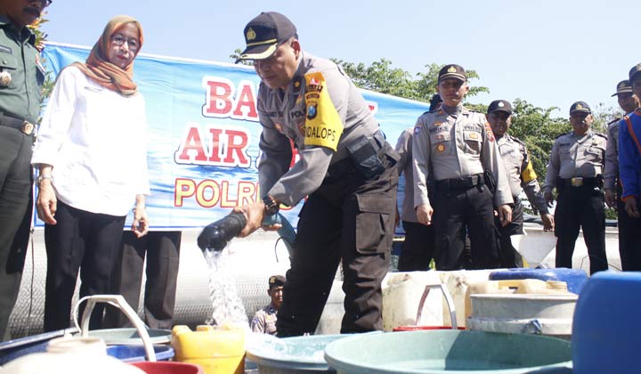 Wakapolres Ngawi Kompol Hartono saat mengisi bak air milik warga yang sudah diantrekan.