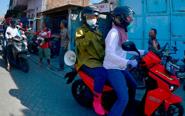 Bonceng Sepeda Motor, Risma Bagikan Masker dan Sosialisasi Protokol Kesehatan