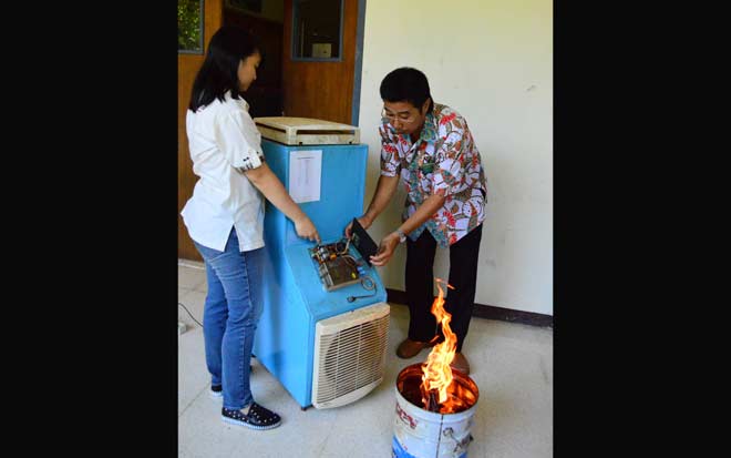 Erlina Wati Halim bersama dan dosen pembimbing Andrew Joewono mempraktekkan kinerja alat filtrasi asap.