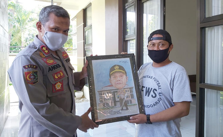 Wakapolresta Sidoarjo AKBP M Anggi Naulifar Siregar mendapatkan kenang-kenangan dari wartawan Sidoarjo sebelum pindah tugas. Kenang-kenangan berupa karikatur itu diberikan oleh wartawan BANGSAONLINE.com, Catur 'Gogon' Andy.