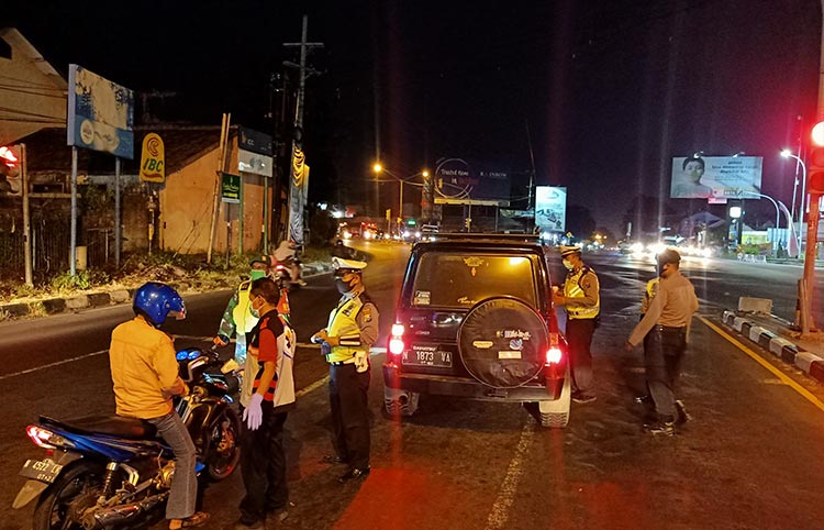 Personel Satlantas Polres pasuruan dibantu anggota Pemuda Pancasila saat memberikan imbauan kepada pengemudi untuk menerapkan physical distancing di Kecamatan Pandaan, Kabupaten Pasuruan.