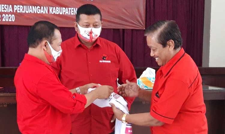 Ketua DPC PDIP Kabupaten Kediri, Murdi Hantoro (kiri) dan Sekretaris DPC PDIP Kabupaten Kediri, Dodi Purwanto (tengah) saat menyerahkan secara simbolis kaos dan makser bergambar Dhito, kepada salah satu pengurus PAC PDIP Kecamatan Pagu, Kediri, Sabtu (19/9/2020). foto: Muji Harjita/ bangsaonline.com.