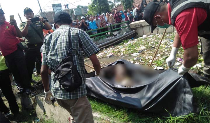 Petugas dibantu warga mengevakuasi mayat yang ditemukan di tumpukan sampah.