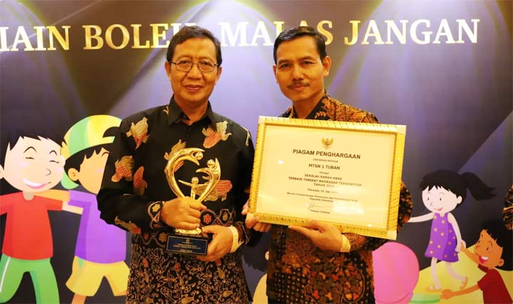 Bupati Tuban H. Fathul Huda dan Kepala MTs Negeri 1 Tuban Tasmo menunjukkan trofi dan piagam penghargaan Madrasah Ramah Anak.