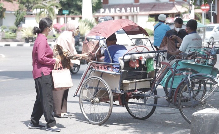 Staf Bagian Protokol dan Komunikasi Pimpinan Pemkot Kediri yang berkolaborasi dengan PWI dan IJTI saat membagikan makanan kepada tukang becak. foto: ist.