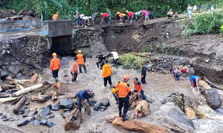 Petugas BPBD Blitar dibantu warga saat melakukan pembersihan jembatan putus akibat banjir bandang di Dusun Barurejo, Desa Krisik, Kecamatan Gandusari.