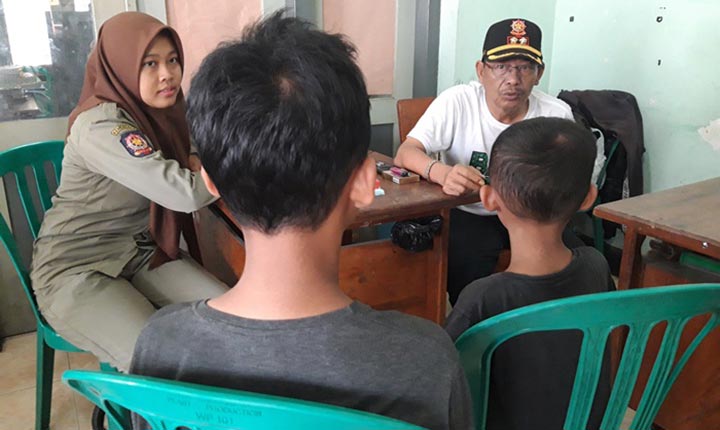 Kabid Trantibum Salpol PP Kota Kediri, Nur Khamid, saat mengajak bicara RP (12 tahun) dan adiknya, GP (7 tahun) di Mako Satpol PP. foto: MUJI HARJITA/ BANGSAONLINE
