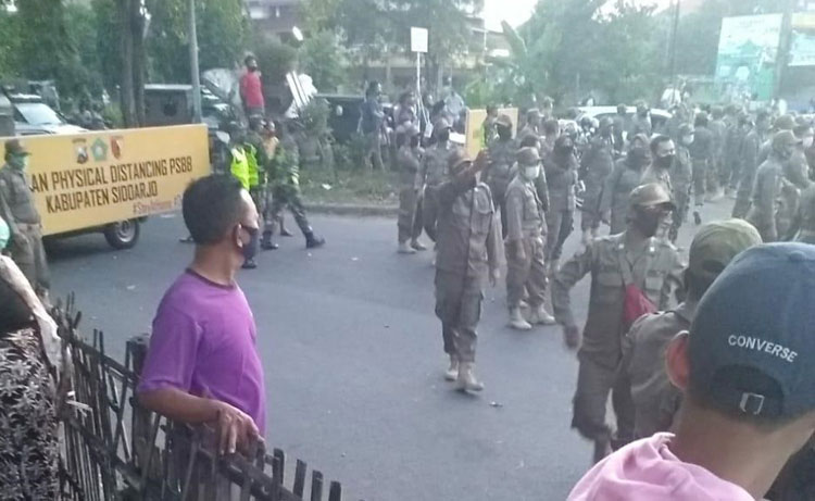 Ratusan petugas Satpol PP turun ke Gading Fajar sambil membawa papan panjang bertuliskan "Areal Physical Distancing".