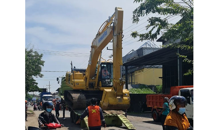 Alat berat didatangkan DPUTR Gresik untuk perbaikan Jalan K.H. Syafi'i Kecamatan Manyar yang rusak parah. (foto: SYUHUD/BANGSAONLINE)