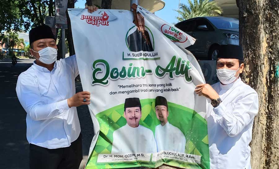 Paslon QA saat membersihkan APK di wilayah GKB. foto: SYUHUD/ BANGSAONLINE
