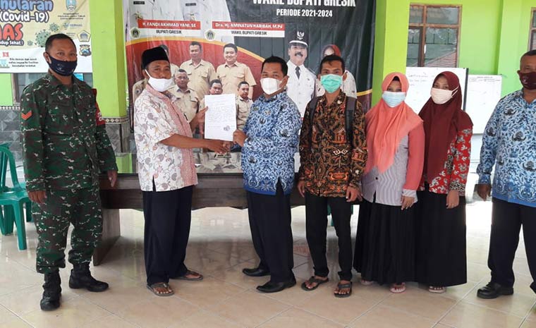 Kepala MI Ma'arif NU Nurul Huda Aliyas, S.Pd.I. dan Kades Sumput Sutaji (kanan) menunjukan naskah kesepakatan bersama PTM dengan penegakan prokes Covid-19. foto: SYUHUD/ BANGSAONLINE.