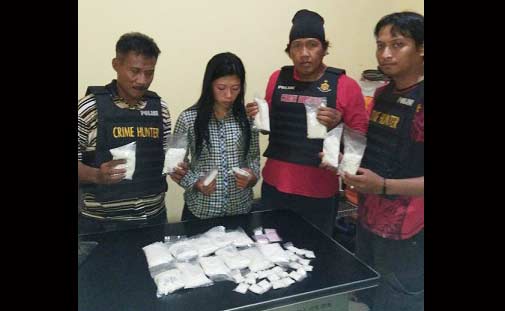 Tersangka pemilik ribuan pil koplo diapit petugas.