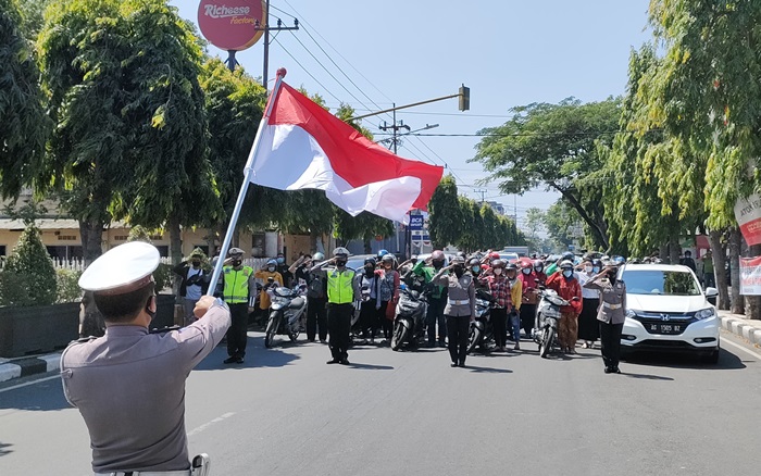 Selasa (17/8) tepat pukul 10.17 WIB, pengguna jalan di depan Mako Satlantas Polres Kediri Kota Jalan Brawijaya, Kota Kediri, berhenti untuk melaksanakan penghormatan kepada Bendera Merah Putih dan menyanyikan lagu Indonesia Raya yang dipandu oleh petugas Satlantas Polres Kediri Kota. foto: MUJI HARJITA/BANGSAONLINE