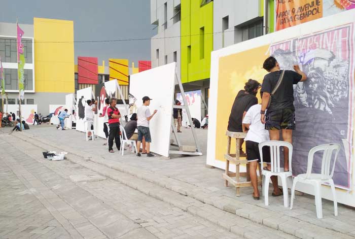 Para seniman mural sedang menunjukkan aksinya melukis pada sebuah media yang disediakan panitia.