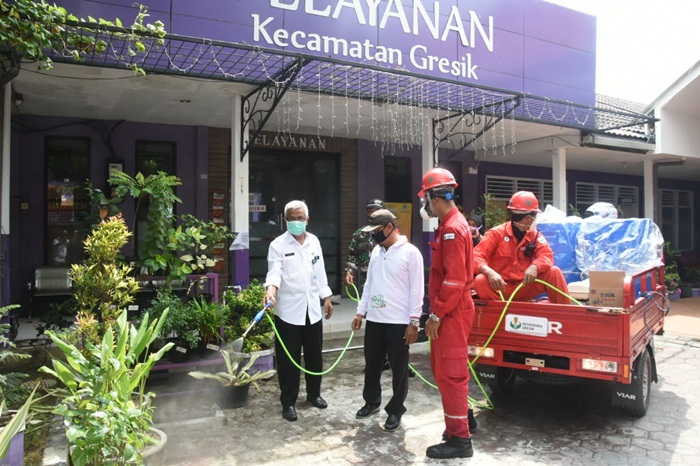 Camat Gresik Purwanto bersama tim dari Petrokimia Gresik saat penyemprotan disinfektan di lingkungan Kantor Kecamatan. foto: ist
