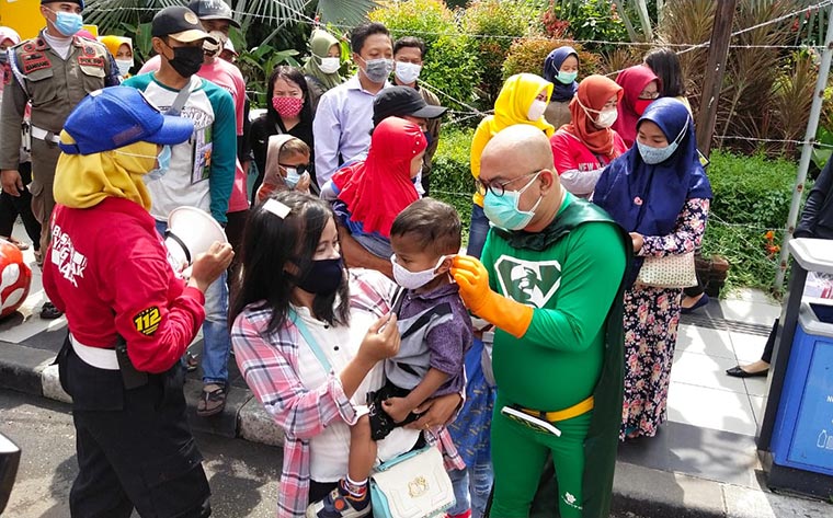 New Man sedang memberikan sekaligus memakaikan masker ke pengunjung anak-anak yang tidak memakai masker di KBS. foto: YUDI A/ HARIAN BANGSA