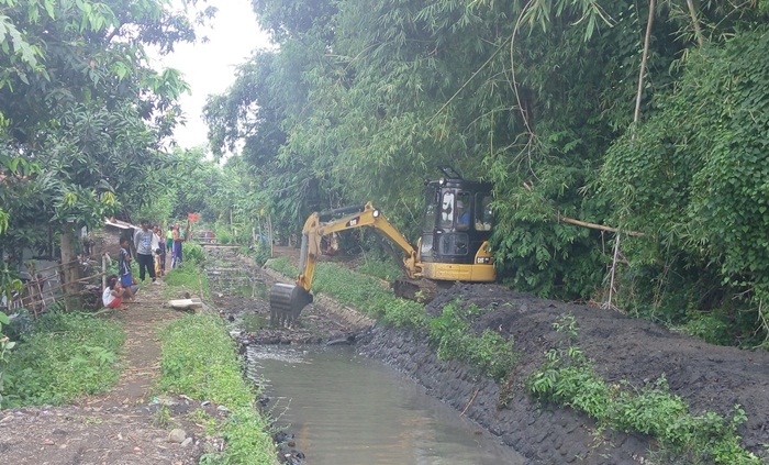 Petugas sedang mengeruk saluran air.