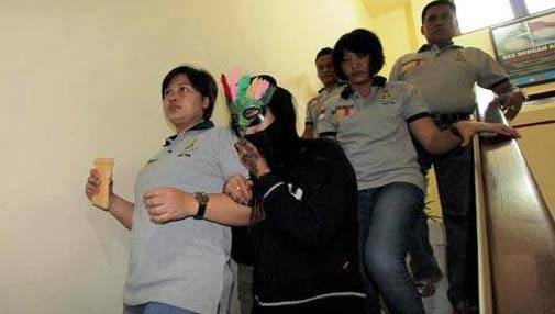 Petugas dari Unit PPA Polrestabes Surabaya menggelandang Putri (mengenakan penutup wajah), Rabu (3/2/2016). foto: suarasurabaya.net