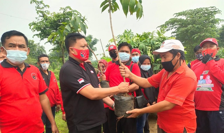 Ketua DPC PDIP Gresik Mujid Riduan didampingi Sekretaris Noto Utomo menyerahkan pohon sebelum ditanam di sekitar areal waduk. foto: ist.