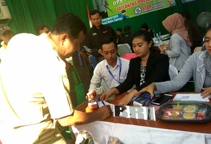 Salah satu pelanggar saat membayar denda ke petugas BRI yang juga disediakan dalam sidang di tempat. foto: ARIF K/ BANGSAONLINE