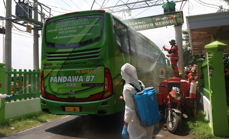 Bus yang akan mengangkut para santri pulang ke daerahnya masing-masing, sedang disemprot dengan cairan disinfektan ketika memasuki pintu gerbang Ponpes Lirboyo. (foto: ist)