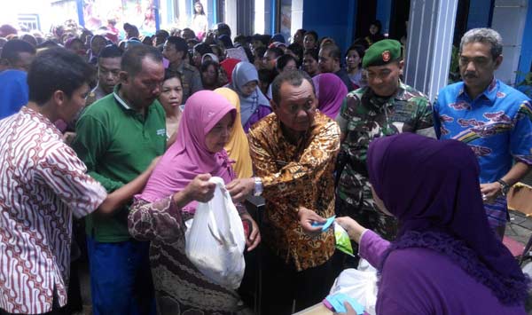 IKUT JUALAN: Pj Bupati Sidoarjo H Jonathan Judianto dan Dandim Sidoarjo Letkol Inf Sarwo Supriyo, sibuk melayani warga di Bazar Bandeng Sidoarjo, Rabu (23/12/2015). foto: musta'in/ BANGSAONLINE