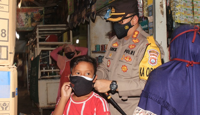 Kapolres Pasuruan AKBP Erick memasangkan masker ke seorang anak di Pasar Pandaan.