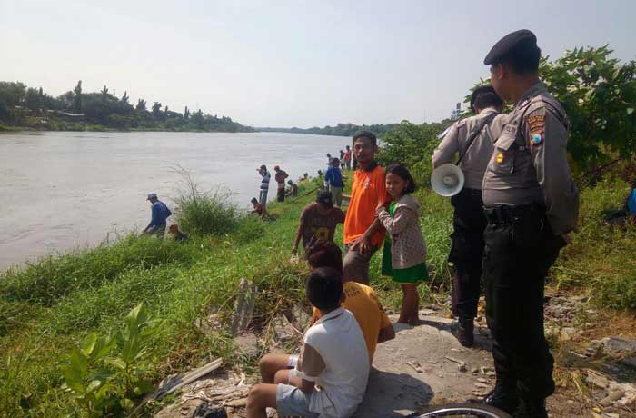 Petugas kepoilisian menggunakan pengeras suara keliling bantara sungai brantas untuk selalu mengingatkan masyarakat agar berhati-hati dalam mencari ikan. foto: ARIF K/ BANGSAONLINE