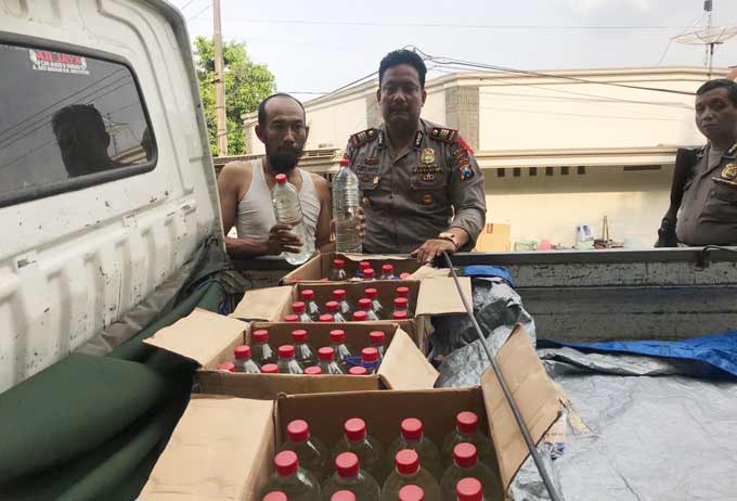 Petugas menunjukkan puluhan botol miras yang disita. foto: SOFFAN/ BANGSAONLINE