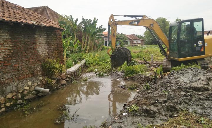 Alat berat melakukan normalisasi saluran pembuangan yang mengalami pendangkalan.