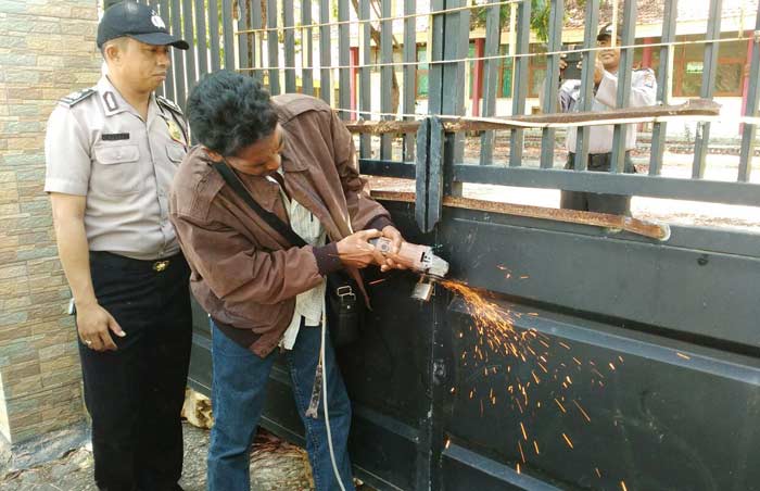 Ahli waris memotong gembok dengan grinda. foto: ERRI S/ BANGSAONLINE